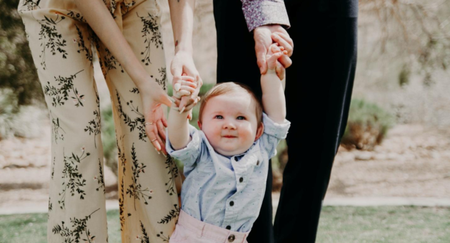 parents holding hands with a baby