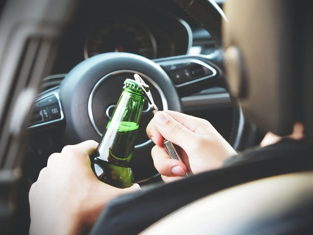  A person opening a beer bottle in a car