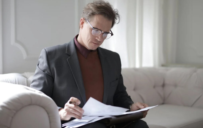 An image of a man looking at some documents while sitting on a couch