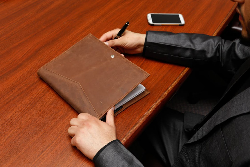 An image of a person holding a brown leather notebook