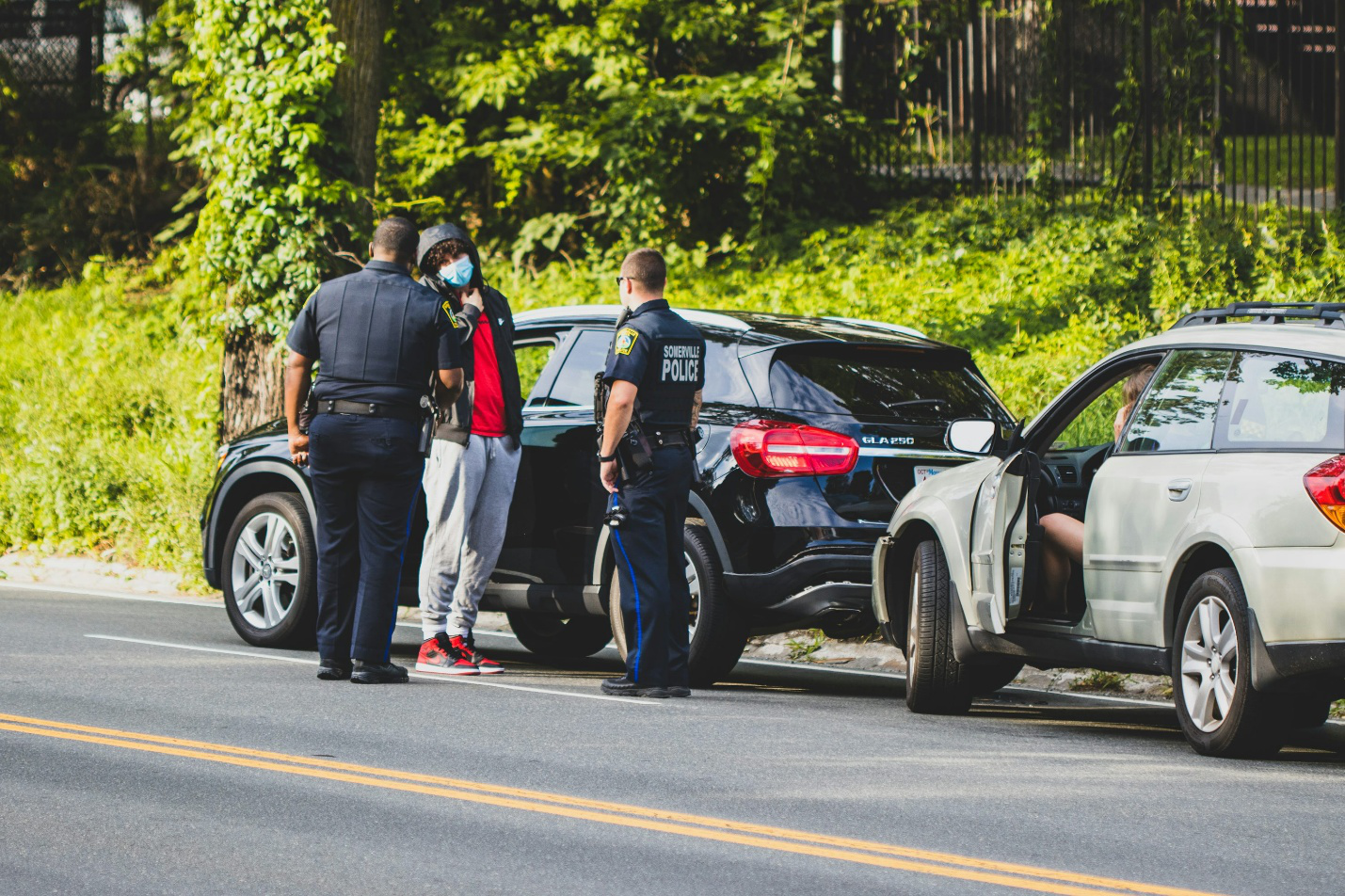 Police officers standing next to a black car before getting a personal injury and damage settlement lawyer