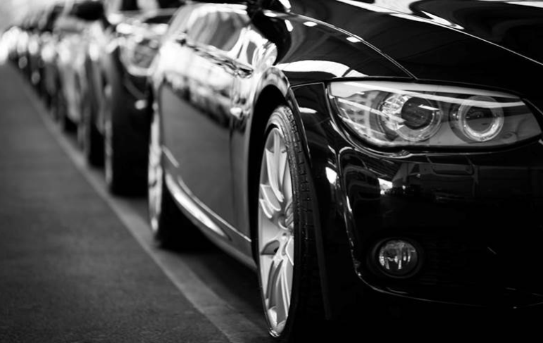 Close-up black and white image of a luxury car line-up.