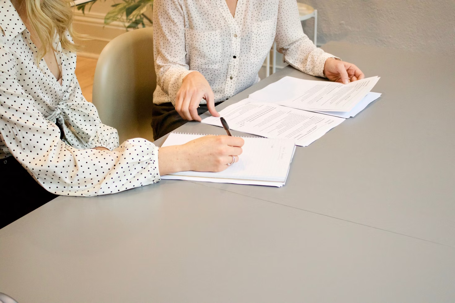 a woman signing papers at a lawyer's office on a grey table