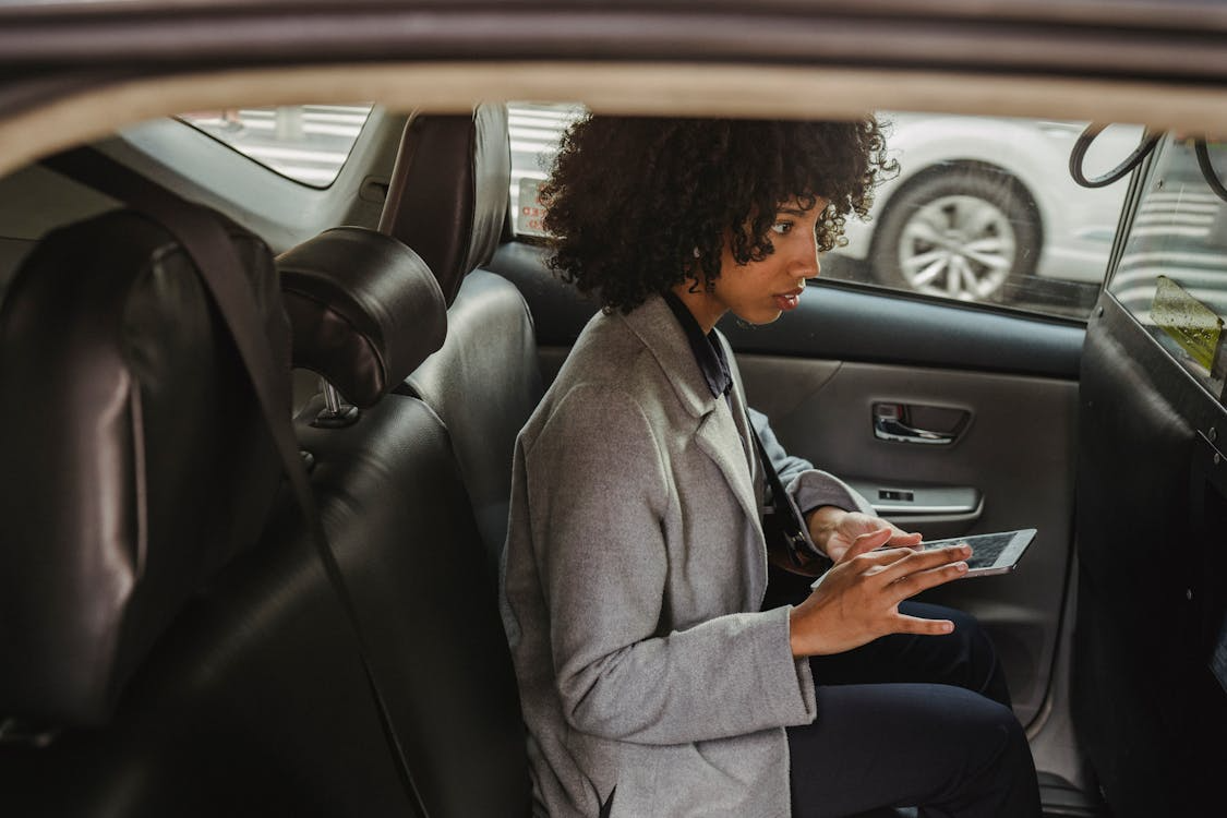 Woman using a tablet inside a car while dealing with ongoing software issues that may qualify for protection under California Lemon Law