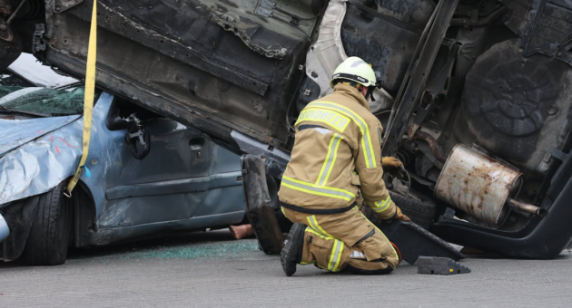a firefighter rescuing someone from an overturned vehicle at an accident scene