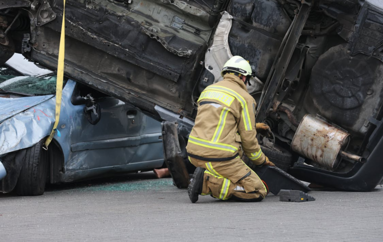 a firefighter rescuing someone from an overturned vehicle at an accident scene