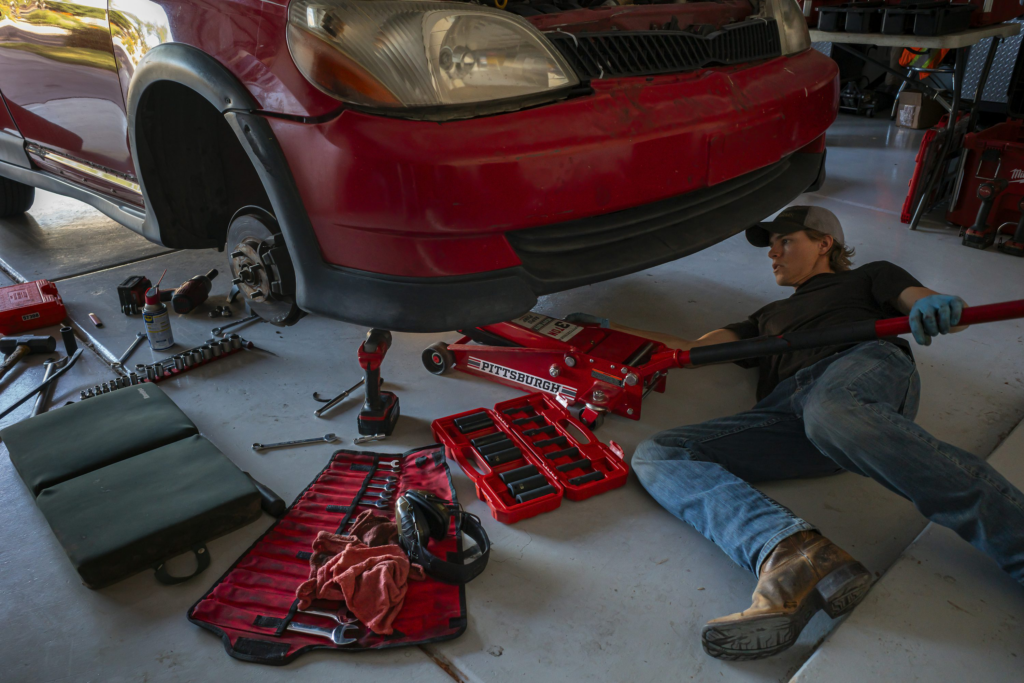 A person working on a car inside a garage  A person working on a car inside a garage