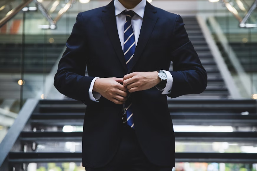 a person in a suit standing near the stairs 