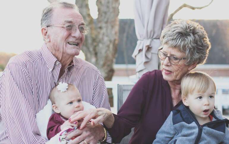 grandparents holding 2 kids