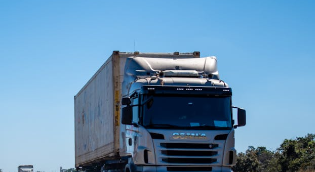 front of a cargo truck on a highway during the day with a blue sky