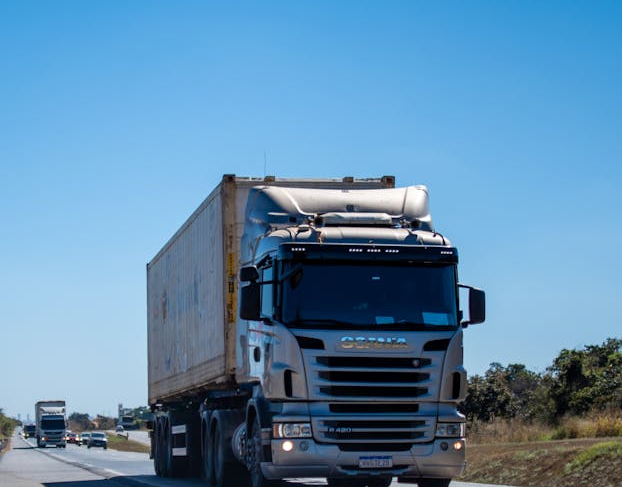 front of a cargo truck on a highway during the day with a blue sky