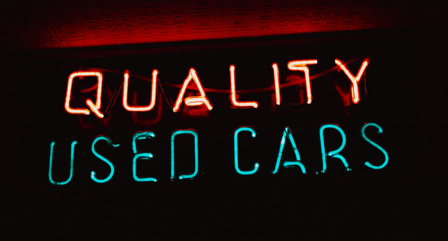 A neon sign promoting available used cars.