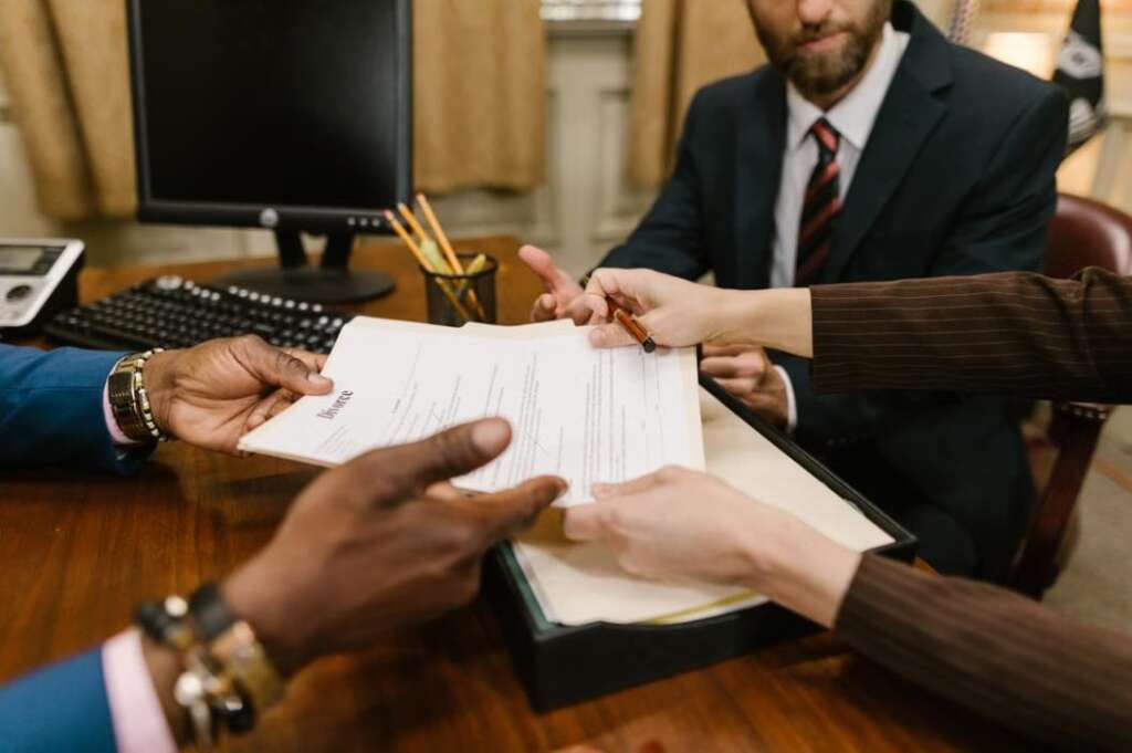 A divorce lawyer reviews paperwork with clients to ensure all details are correct before filing. A divorce lawyer reviews paperwork with clients to ensure all details are correct before filing.